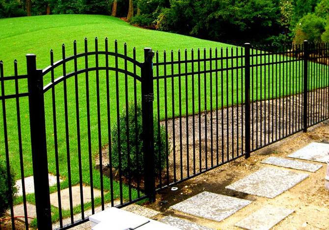 Black aluminum spear-top fence with arched walk gate at the entrance to a backyard garden