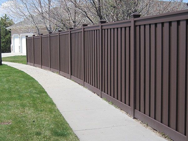 Brown vinyl semi-privacy fence with concave top following a curved walkway