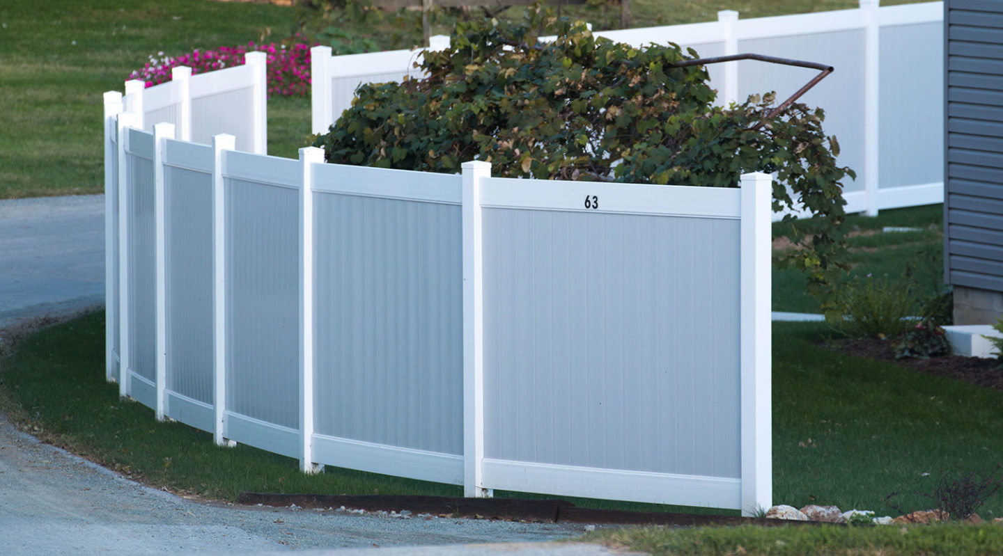 Two-tone gray and white vinyl privacy fence with curved scalloped top following a property line