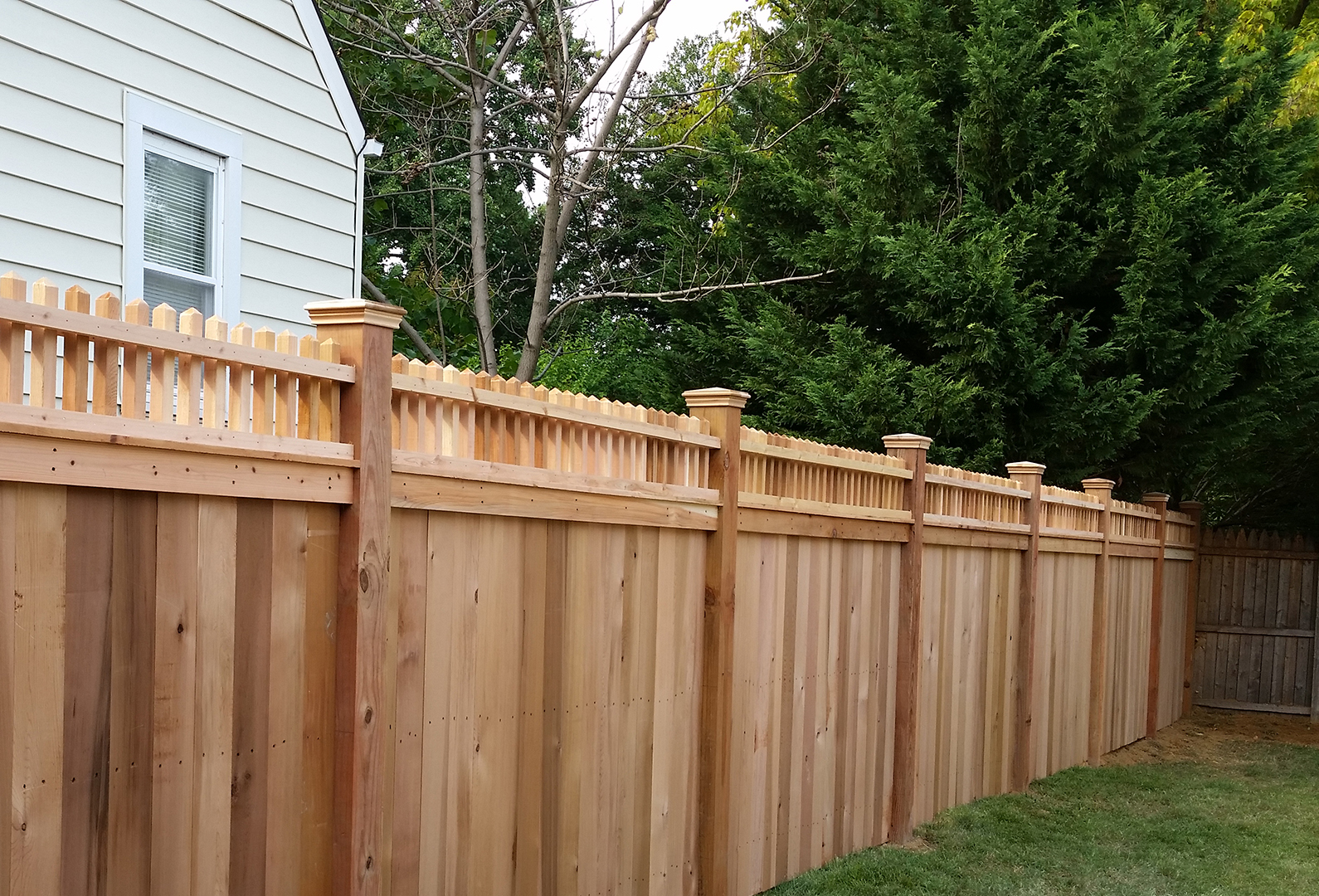 Cedar privacy fence finished with a decorative spindle topper
